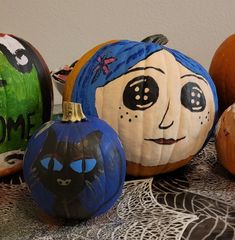 painted pumpkins with faces on them sitting on a table