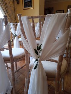 the chairs are decorated with white cloths and green leaves on each chair's sashes