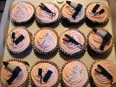 twelve cupcakes with pink frosting and black icing in a cardboard box