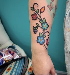 a woman's arm with flowers and butterflies tattooed on the left side of her arm