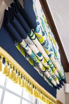 blue and yellow curtains hanging from the side of a window sill with tassels