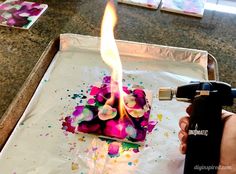 a person is using a lighter to light up a birthday cake with colorful sprinkles