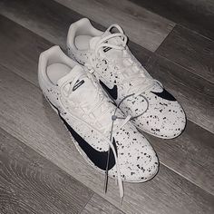 a pair of white and black sneakers on top of a wooden floor