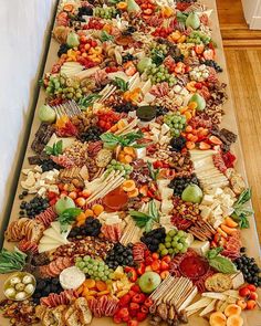 a very long table covered with lots of different types of cheeses and fruits on it