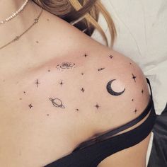 a woman's chest with stars, planets and the moon tattoo on her left side