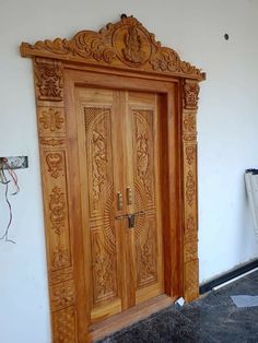 a wooden door with intricate carvings on the front and side panels, in an unfinished room