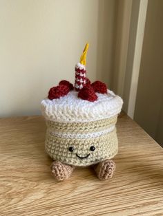 a crocheted cupcake sitting on top of a table with a candle in it