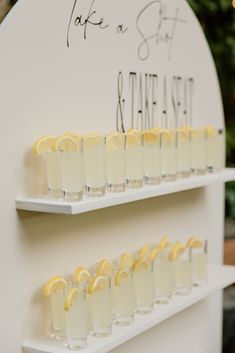 there are many glasses that have lemons in them on the shelf next to each other