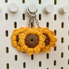 a crocheted sunflower keychain hanging from a hook on a wall