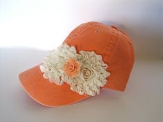 an orange hat with white flowers on the brim and a flower in the center