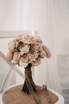 a bouquet of flowers sitting on top of a white chair with a brown ribbon around it