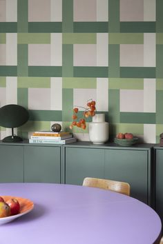 a purple table with fruit on it in front of a green and white wallpaper