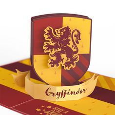 a red and yellow shield with a golden lion on it's side next to a ribbon that says gryffinender