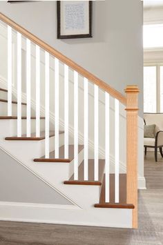 a staircase with white railing and wood handrails in a home setting, along with two framed pictures on the wall