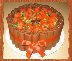 a chocolate cake with strawberries in the middle on a white plate and red ribbon