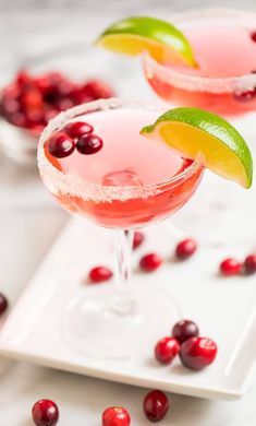 two cranberry margaritas with lime garnish sit on a white plate