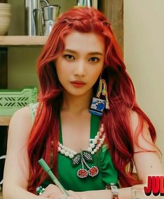 a woman with long red hair sitting at a table