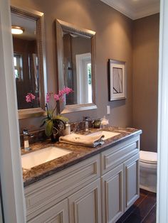 a bathroom with two sinks and a toilet in it's center, along with a large mirror over the sink