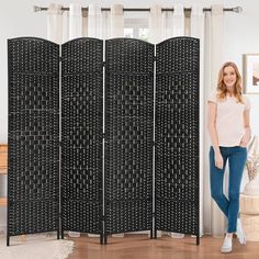 a woman standing in front of a room divider