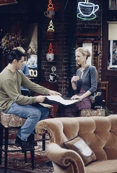 a man and woman sitting at a table in a living room talking to each other