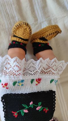 an infant doll is laying on top of a crocheted blanket and wearing knitted shoes