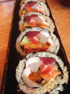 several sushi rolls are lined up on a black plate, ready to be eaten