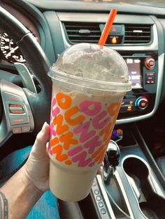 a person holding a drink in their hand while sitting in the driver's seat of a car