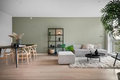 a living room filled with furniture next to a large window covered in greenery and potted plants