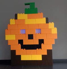 an orange made out of legos sitting on top of a black floor next to a gray wall