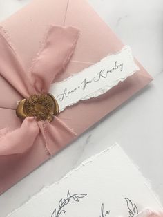 two pink and white wedding cards with ribbon on them, one has a wax stamp