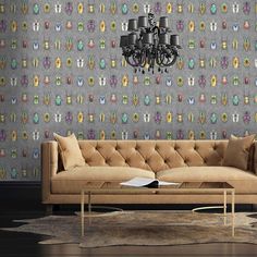 a couch sitting in front of a chandelier next to a table with a book on it