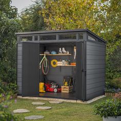 an outdoor storage shed with its doors open and tools on the shelves in front of it