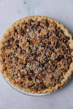 a pie sitting on top of a metal pan covered in nuts and other toppings