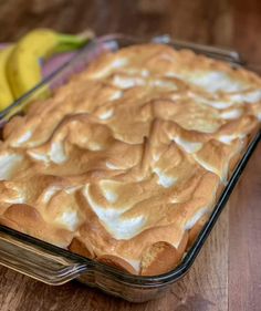 a glass baking dish filled with some kind of dessert next to bananas on a wooden table