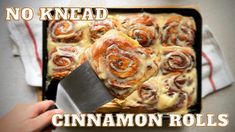 there is a pan filled with cinnamon rolls and a knife next to it that says no knead