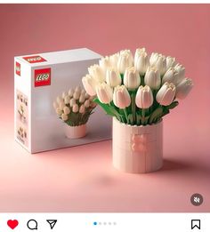 a vase filled with white tulips sitting next to a box of lego blocks