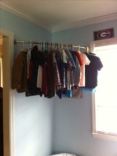 a bunch of clothes hanging on a rail in a room with a bed and window