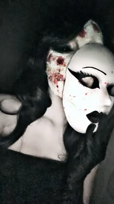 a woman wearing a white mask with blood all over her face and black hair in the dark