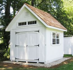 a small white shed with a brown roof