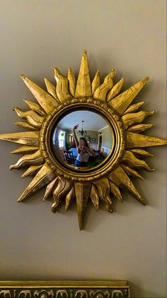 a mirror that is on the wall in front of a sunburst shaped object