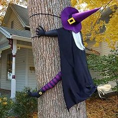 a scarecrow is hanging on the side of a tree in front of a house