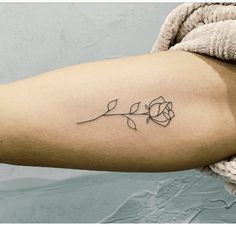 a woman's arm with a single rose tattoo on the left side of her arm