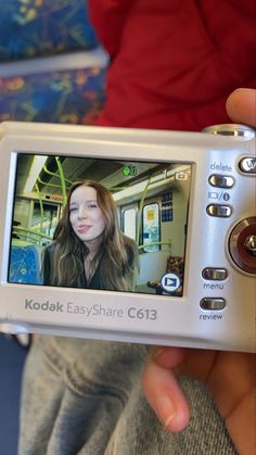 a person holding up a camera with a girl on it's screen in front of them