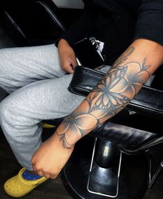 a person sitting in a chair with a tattoo on their arm and leg, holding a wallet