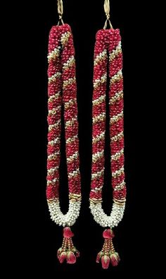 red and white beaded earrings with tassels hanging from them on a black background