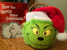 a grinch pumpkin sitting on top of a table next to a book