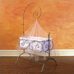 a baby's cradle with two white balls in it and an orange wall behind it