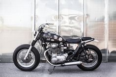 a black and silver motorcycle parked in front of a metal wall with graffiti on it