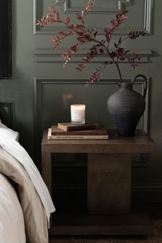 a vase with flowers on a table next to a bed