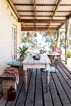 an outdoor dining area with wooden flooring and white table surrounded by blue cushions on chairs